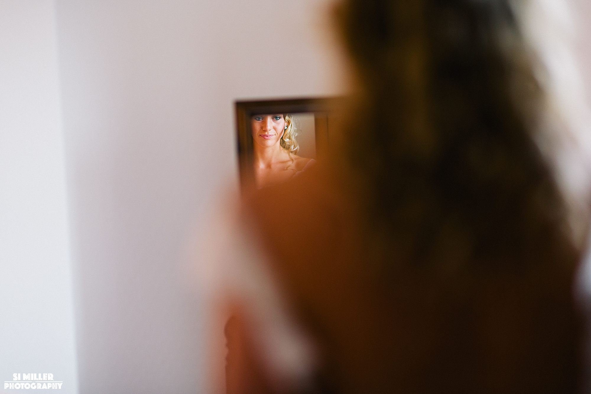 bride looking into mirror in her wedding dress at home in Preston