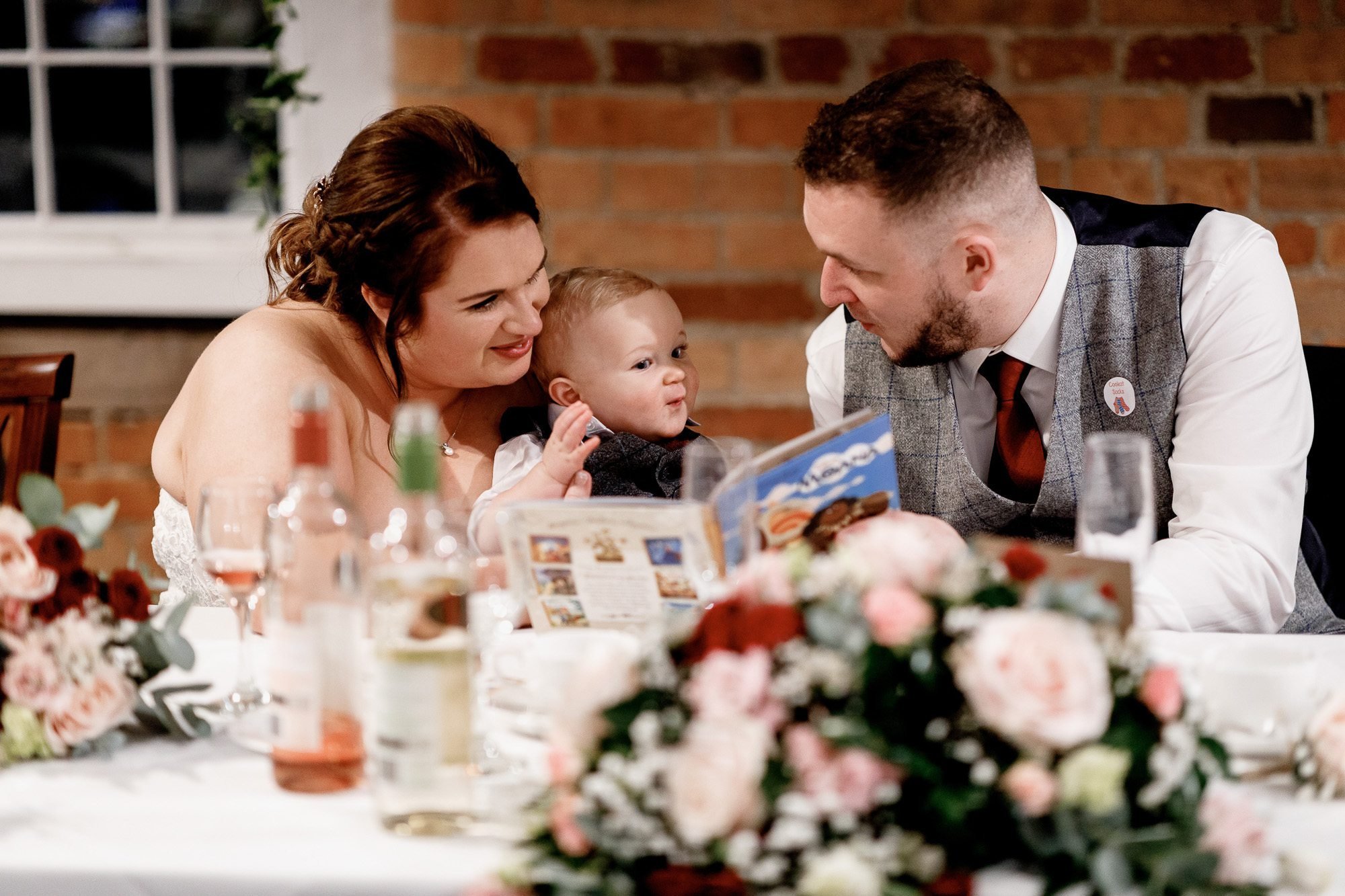 Bride and groom reading to baby son during wedding breakfast